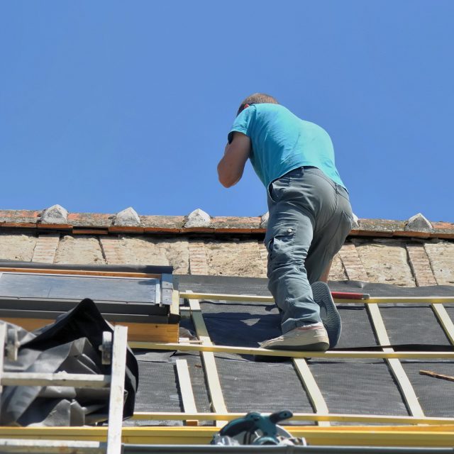 roofer on the top put a waterproof film on a roof